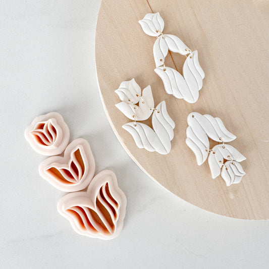 Pair of white floral earrings on a wooden stand with a white background